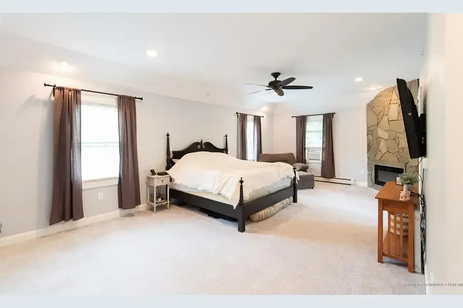 A large bedroom with a king size bed and a fireplace.
