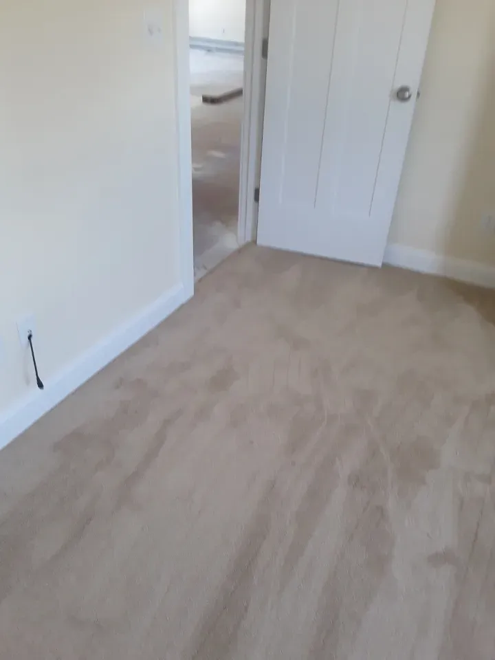 An empty room with a door and a carpeted floor.