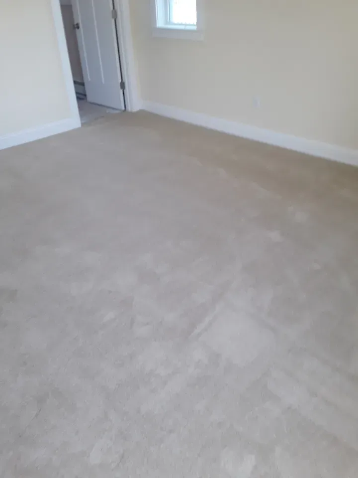 A bedroom with a carpeted floor and white walls.