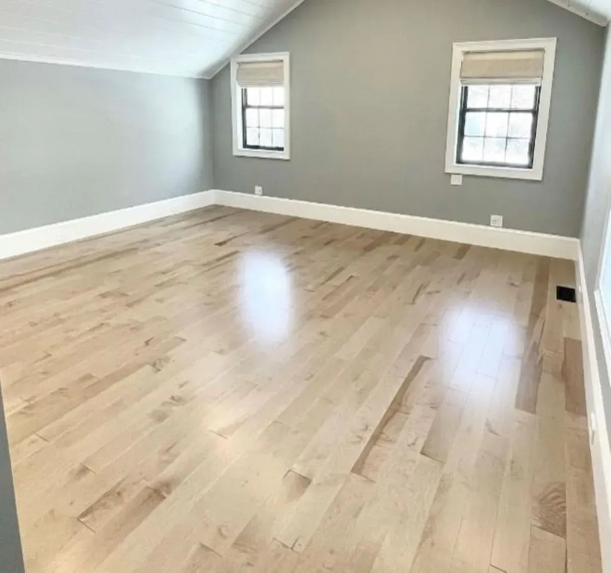 An empty room with hardwood floors and gray walls