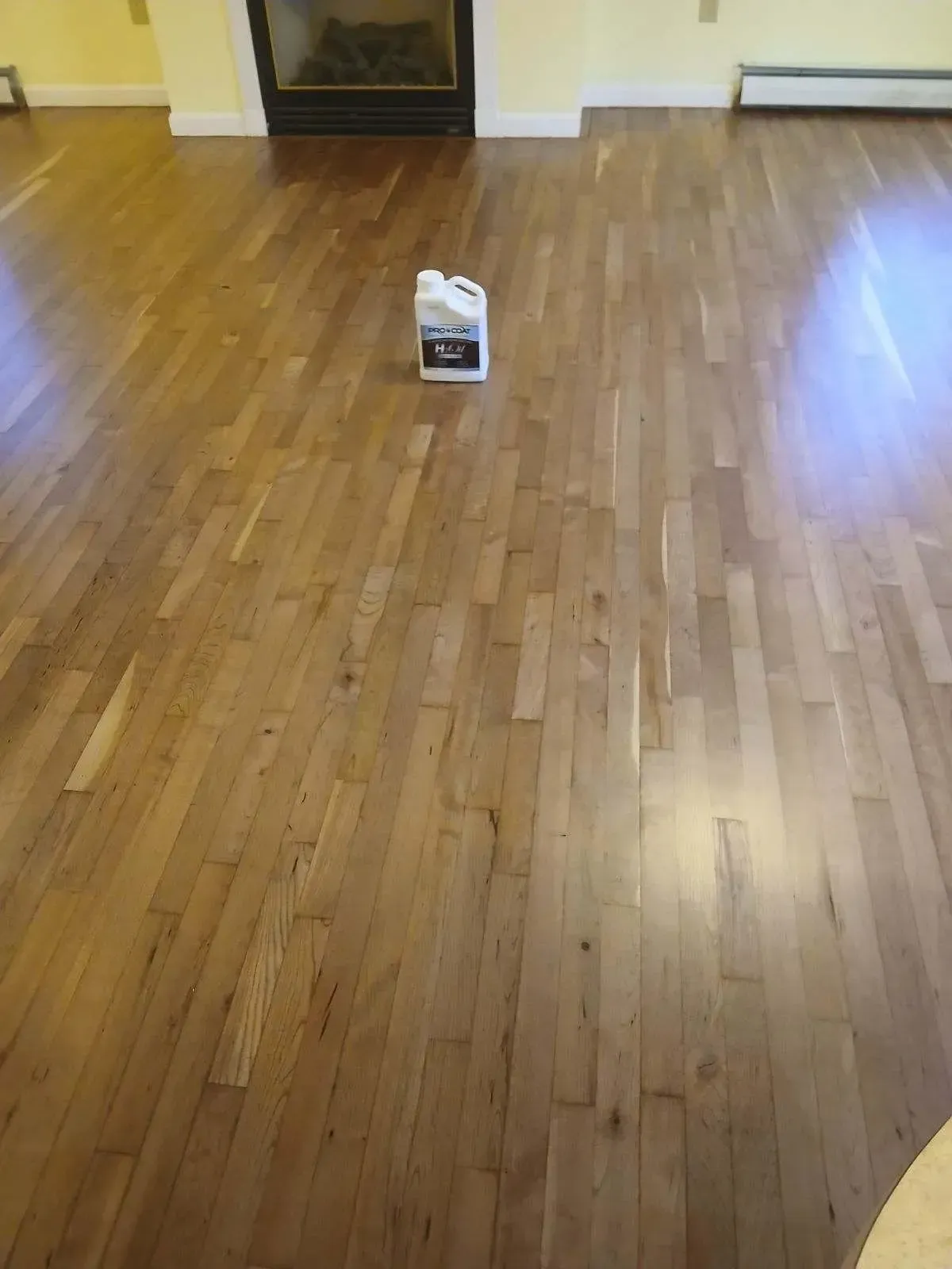 A bottle of cleaner is sitting on a wooden floor