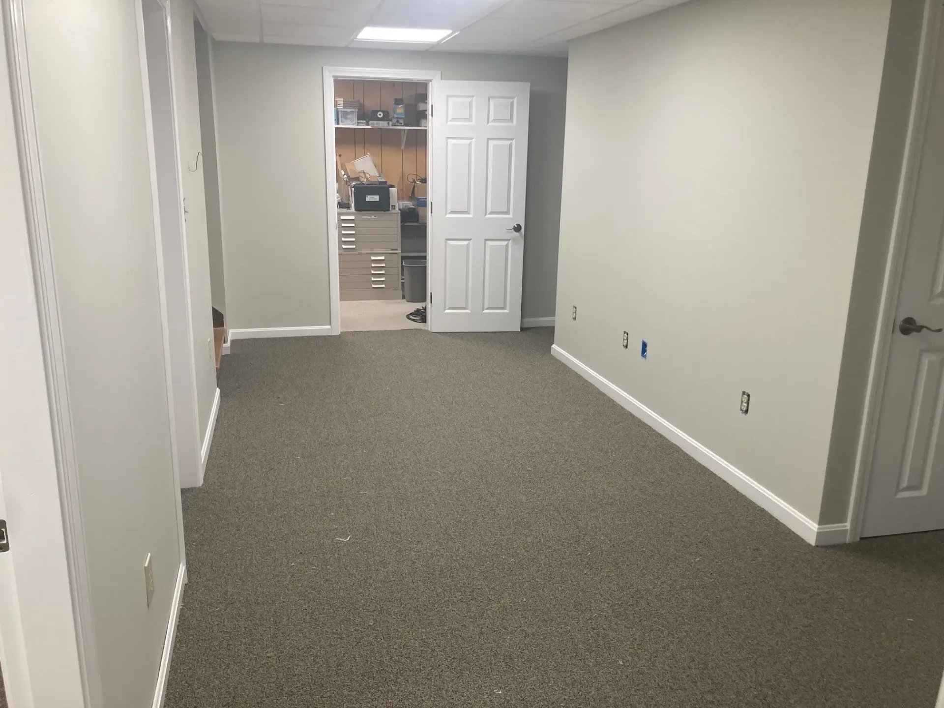 An empty room with a carpeted floor and a door leading to a closet.