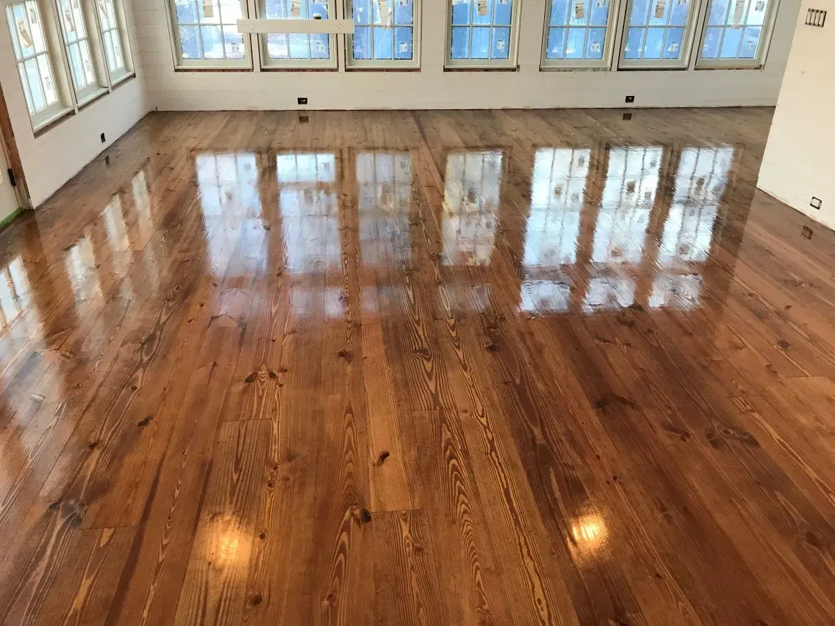 A large room with a wooden floor and lots of windows.