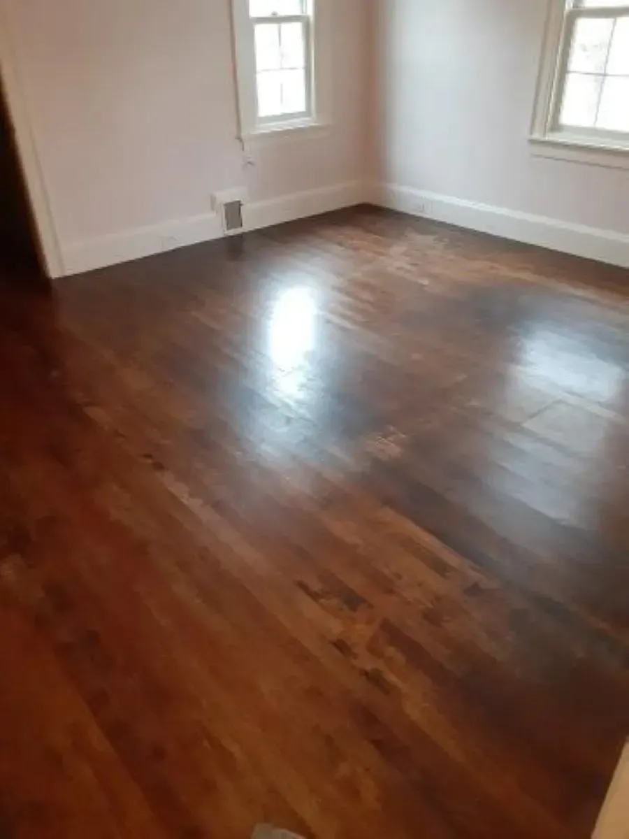 A living room with hardwood floors and two windows.