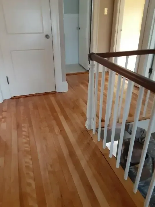 A hallway with hardwood floors and a white railing