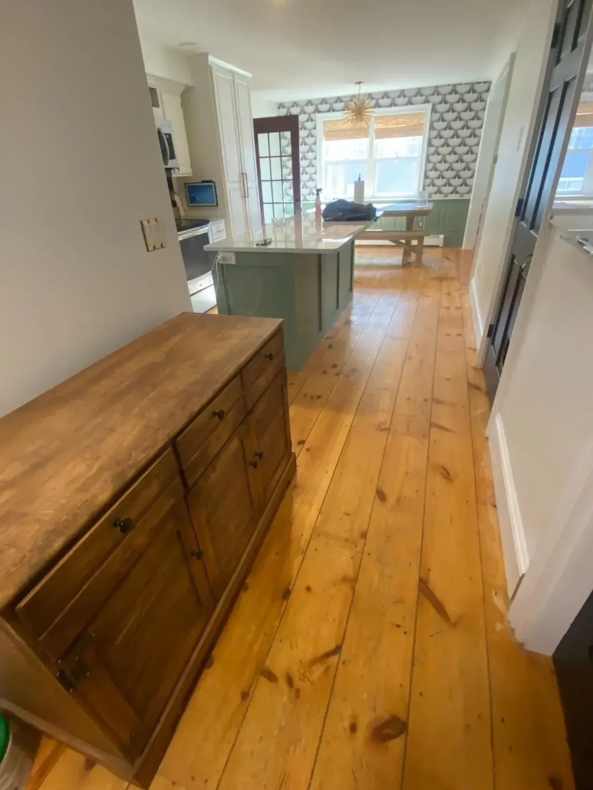A hallway with wooden floors and a dresser in the middle