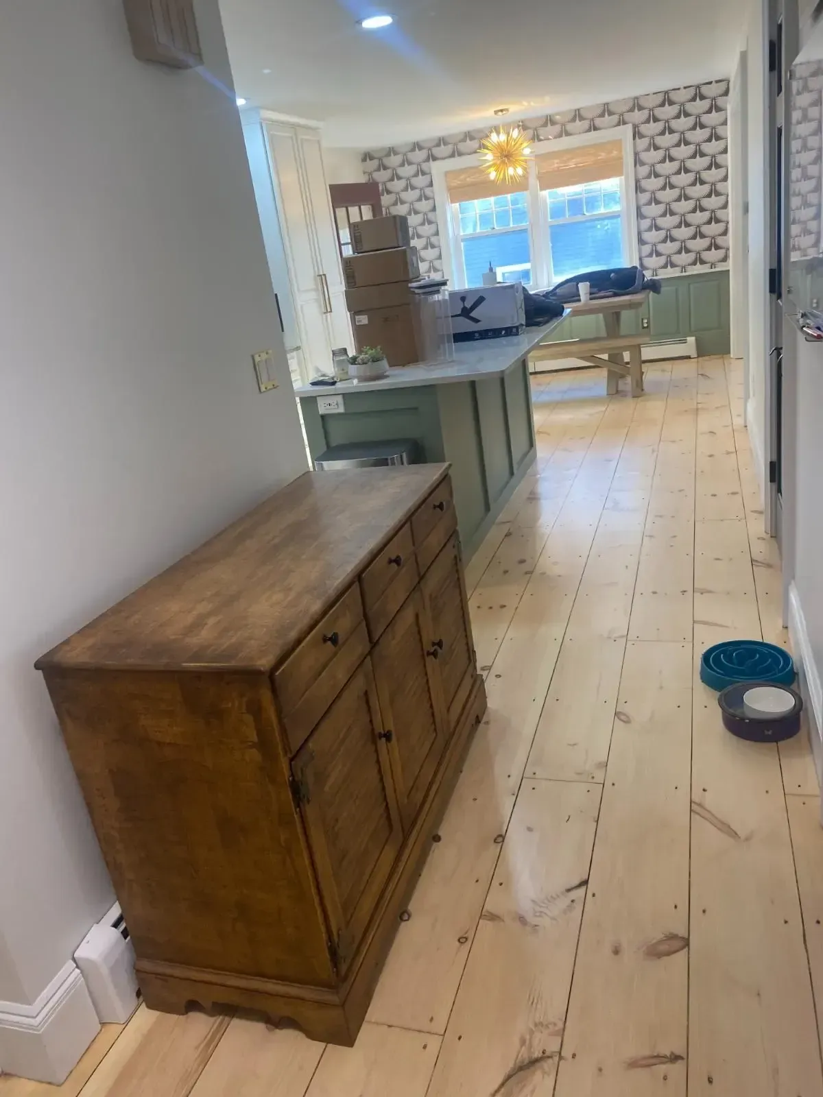 A wooden dresser is sitting in a hallway next to a wooden floor.
