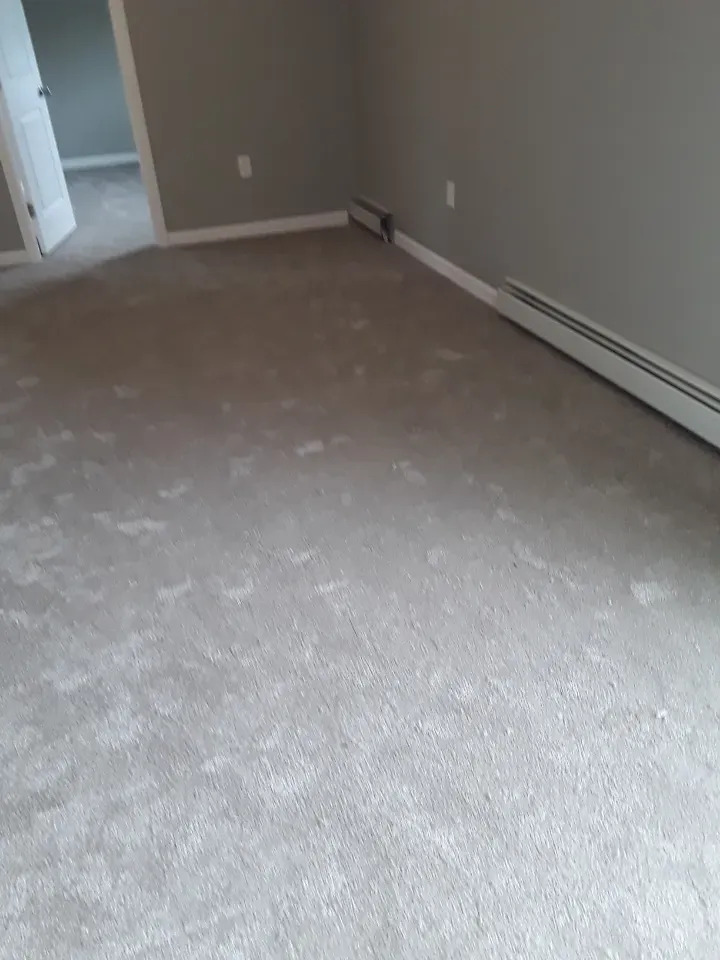 A room with a carpeted floor and a radiator on the wall.