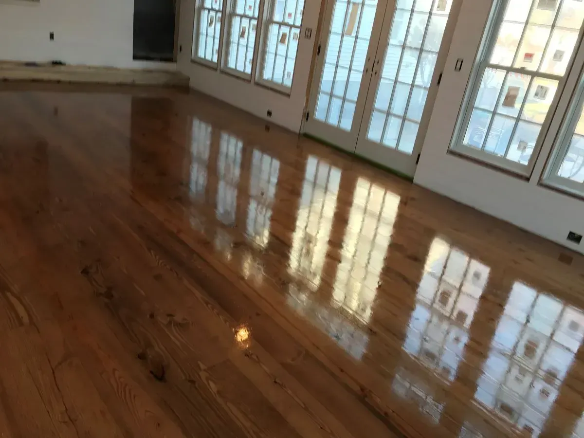 A large room with a wooden floor and lots of windows