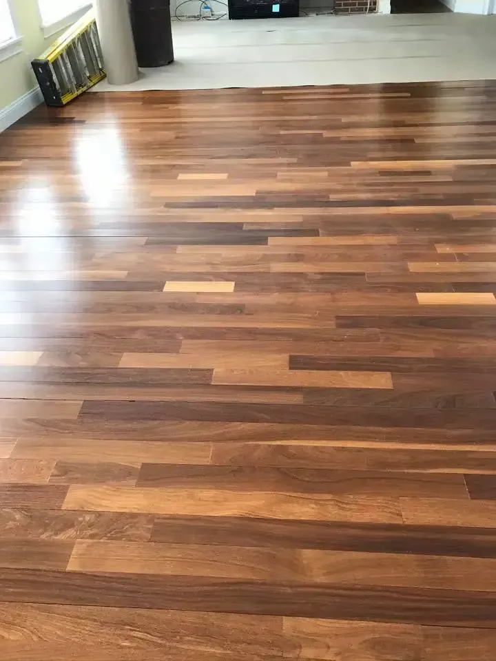 A wooden floor in a living room with a ladder in the background.