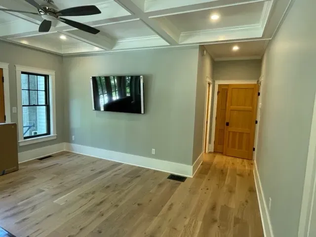 A living room with hardwood floors and a flat screen tv on the wall