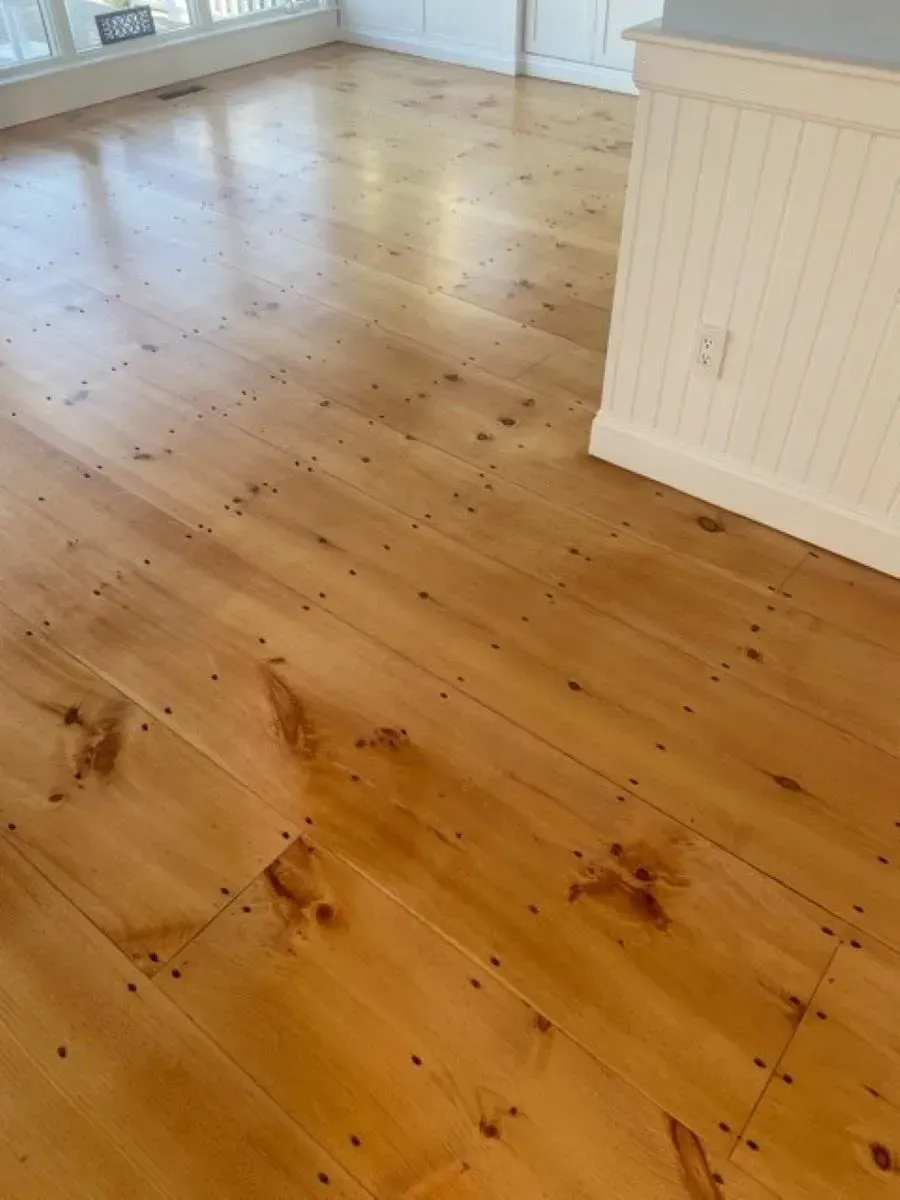 A wooden floor in a living room with a white cabinet.