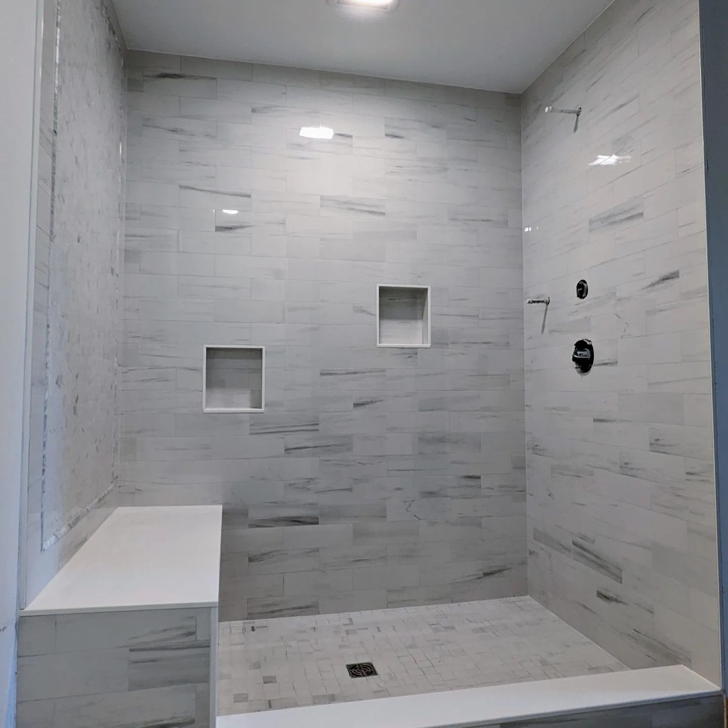 A bathroom with a walk in shower and a bench.
