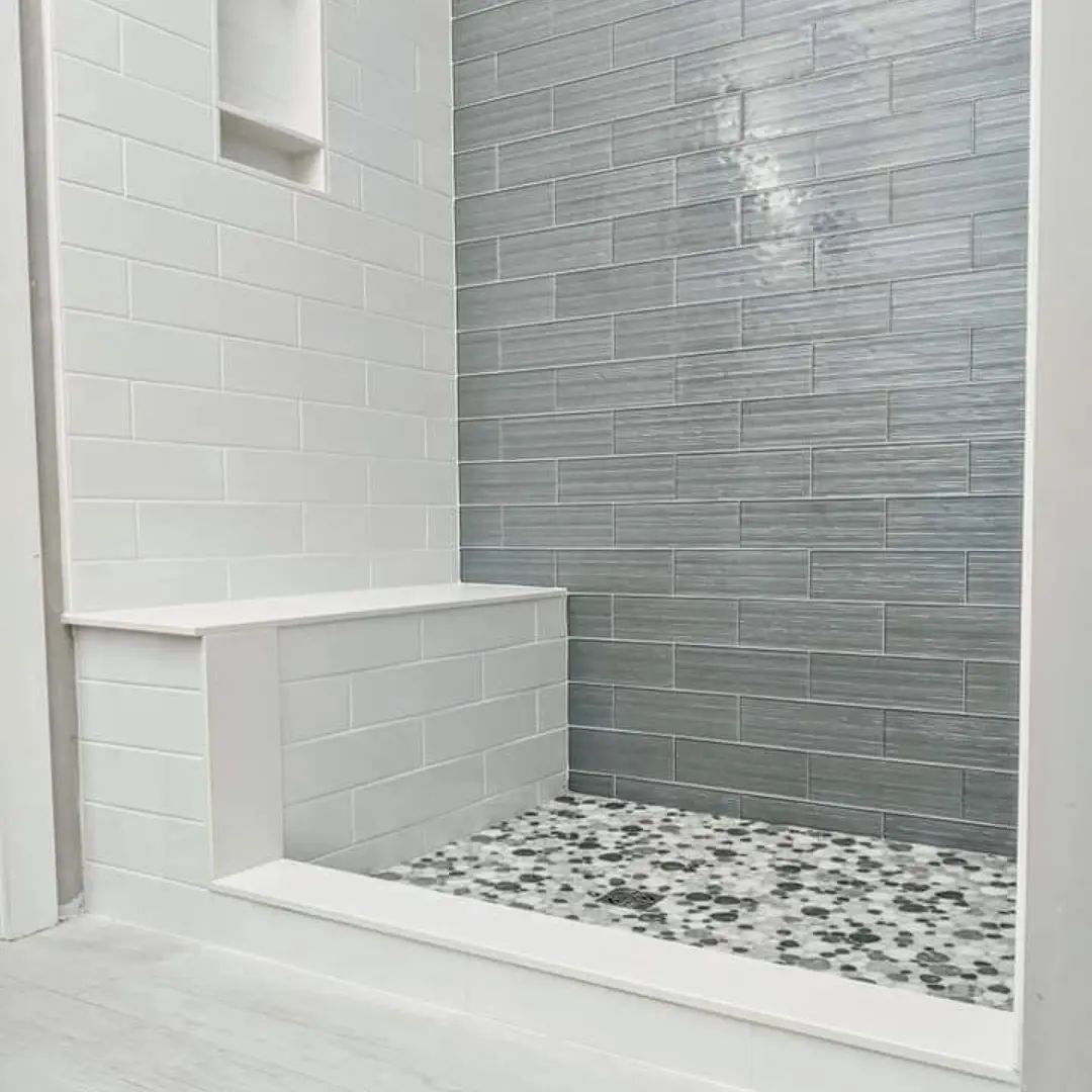 A bathroom with a walk in shower and a bench.