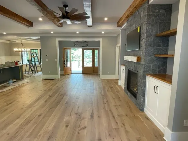 A living room with hardwood floors , a fireplace and a ceiling fan.