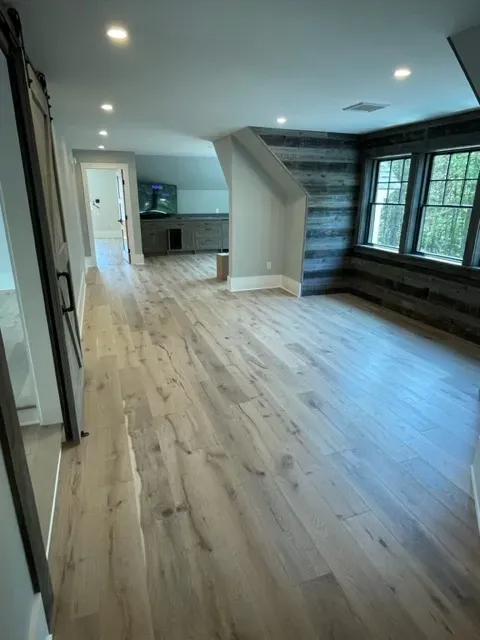 A large empty room with hardwood floors and lots of windows.