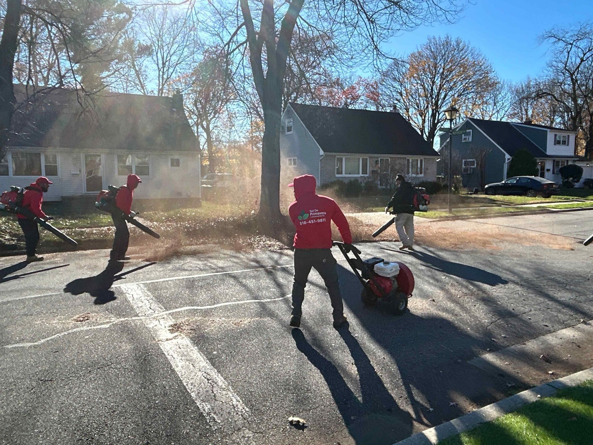 People in red jackets playing street hockey on a sunny residential road