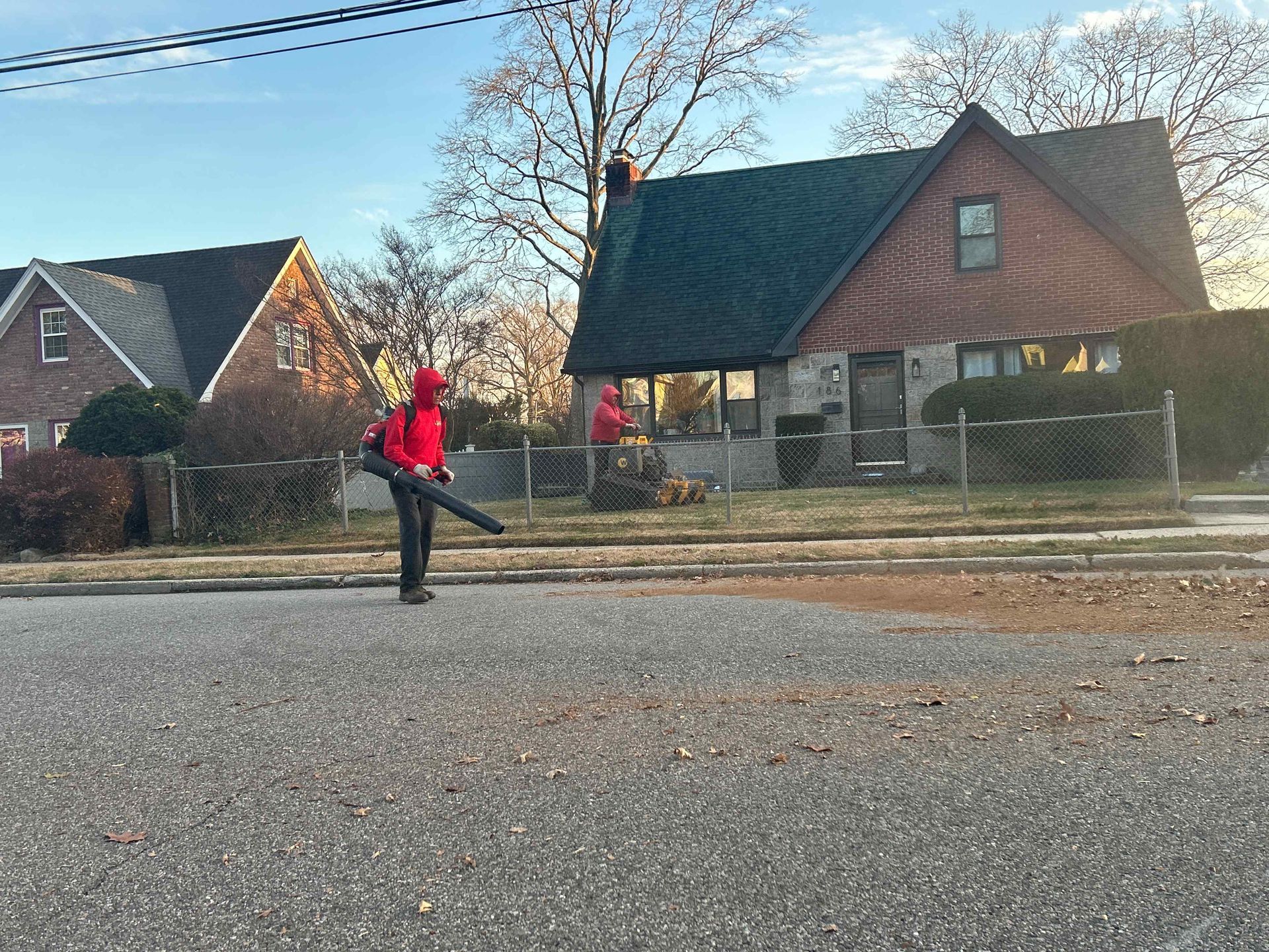 Person in a red jacket standing on a gravel street in front of houses on a sunny day