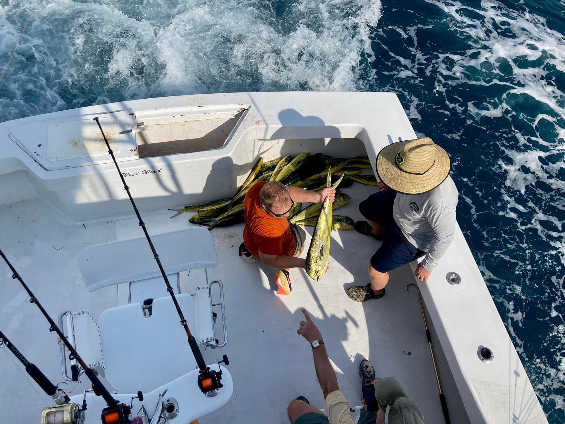 People on a boat with a pile of fish. One person is pointing.