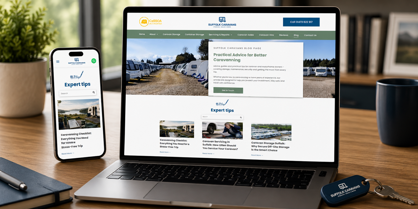 Laptop and phone displaying Suffolk Caravans website on a desk beside a camera and coffee mug.