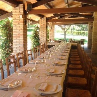Tavolo del ristorante apparecchiato con bicchieri e vista dalla finestra, un quadro con tre vecchie foto sulla parete.