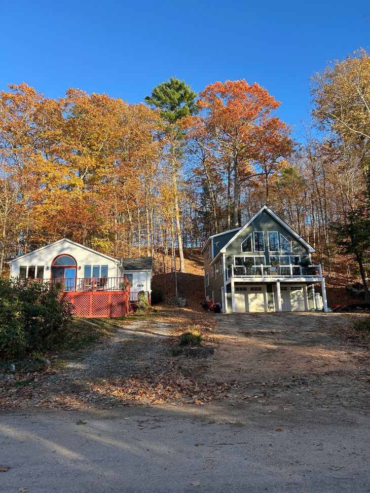 Two houses under autumn trees with colorful fall foliage and a clear blue sky