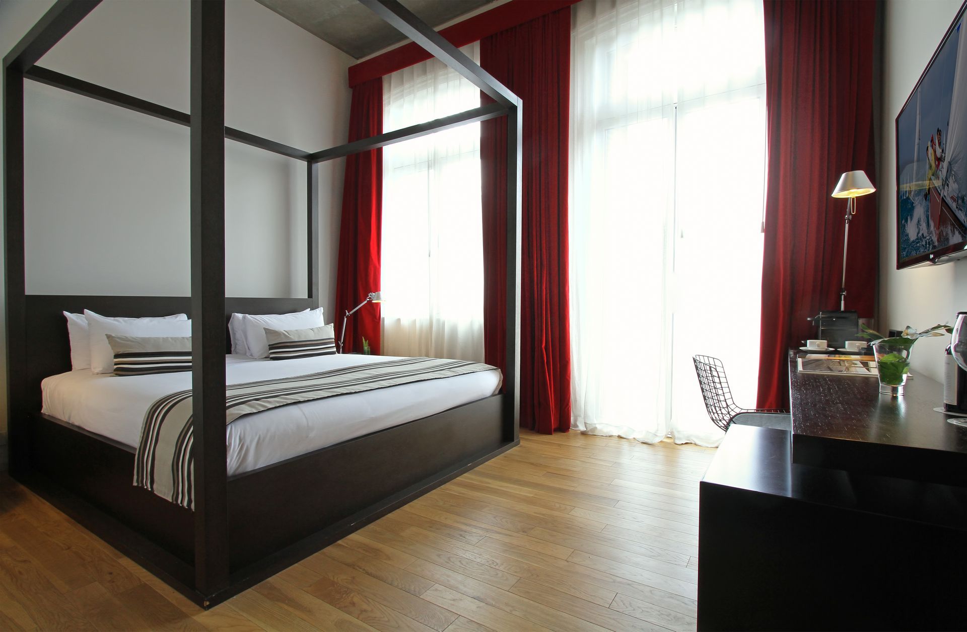 Una cama con dosel en una habitación de hotel con cortinas rojas.