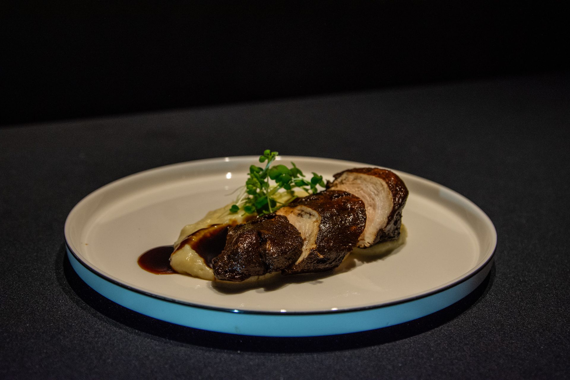 Un plato blanco cubierto con carne y puré de patatas sobre una mesa.