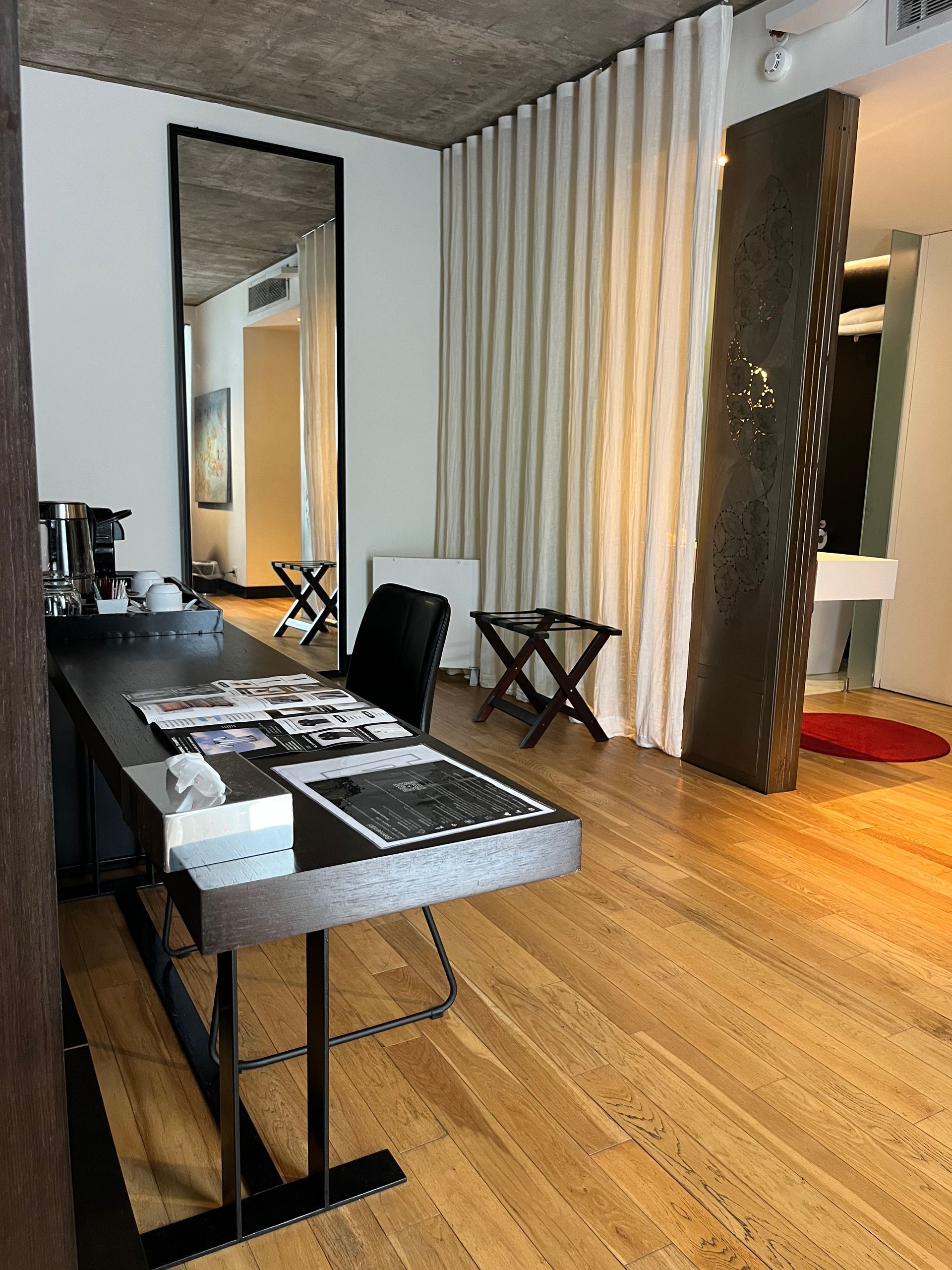 Una habitación con pisos de madera, un escritorio y un gran espejo.