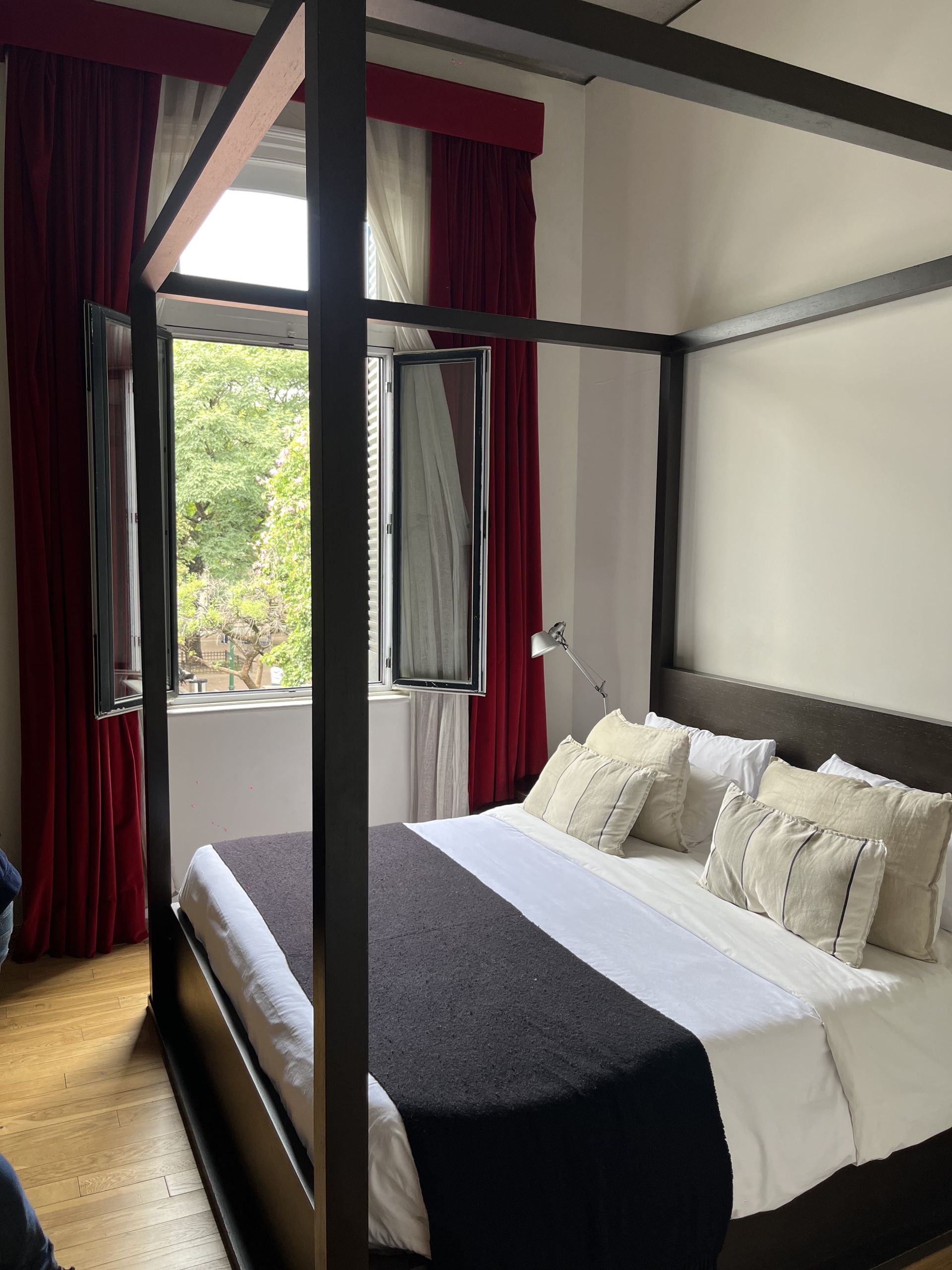 Una cama con dosel en una habitación de hotel con cortinas rojas.