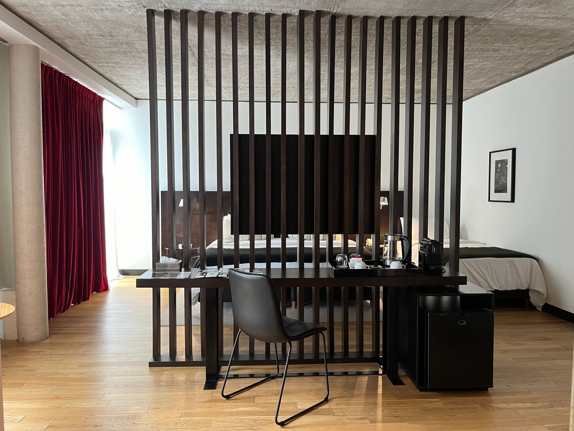 Una habitación de hotel con dos camas y una otomana negra