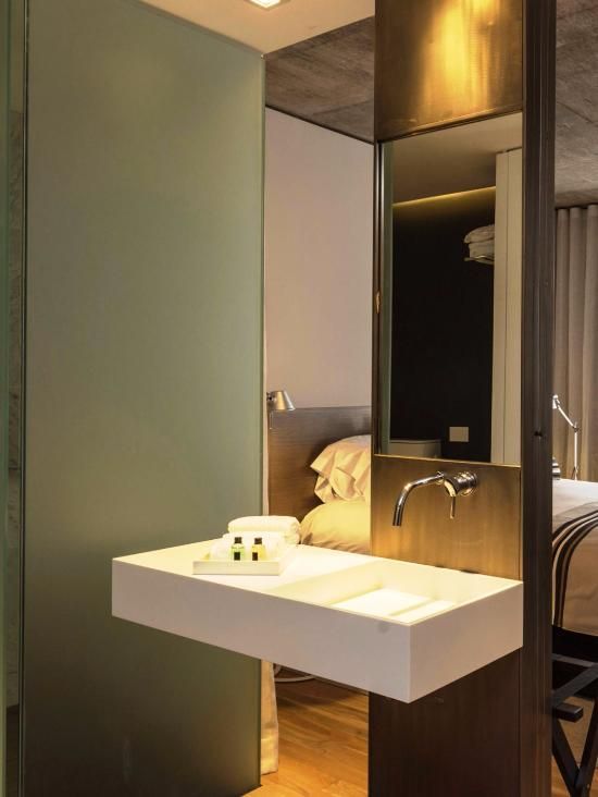 Un baño con lavabo y espejo al lado de una cama