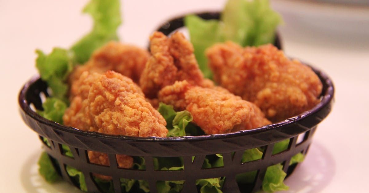 Una canasta llena de pollo frito y lechuga sobre una mesa.