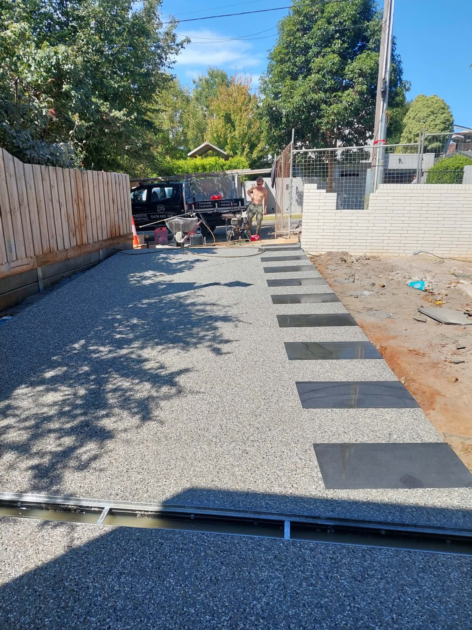 Curved black gravel driveway beside brick house and trimmed hedges