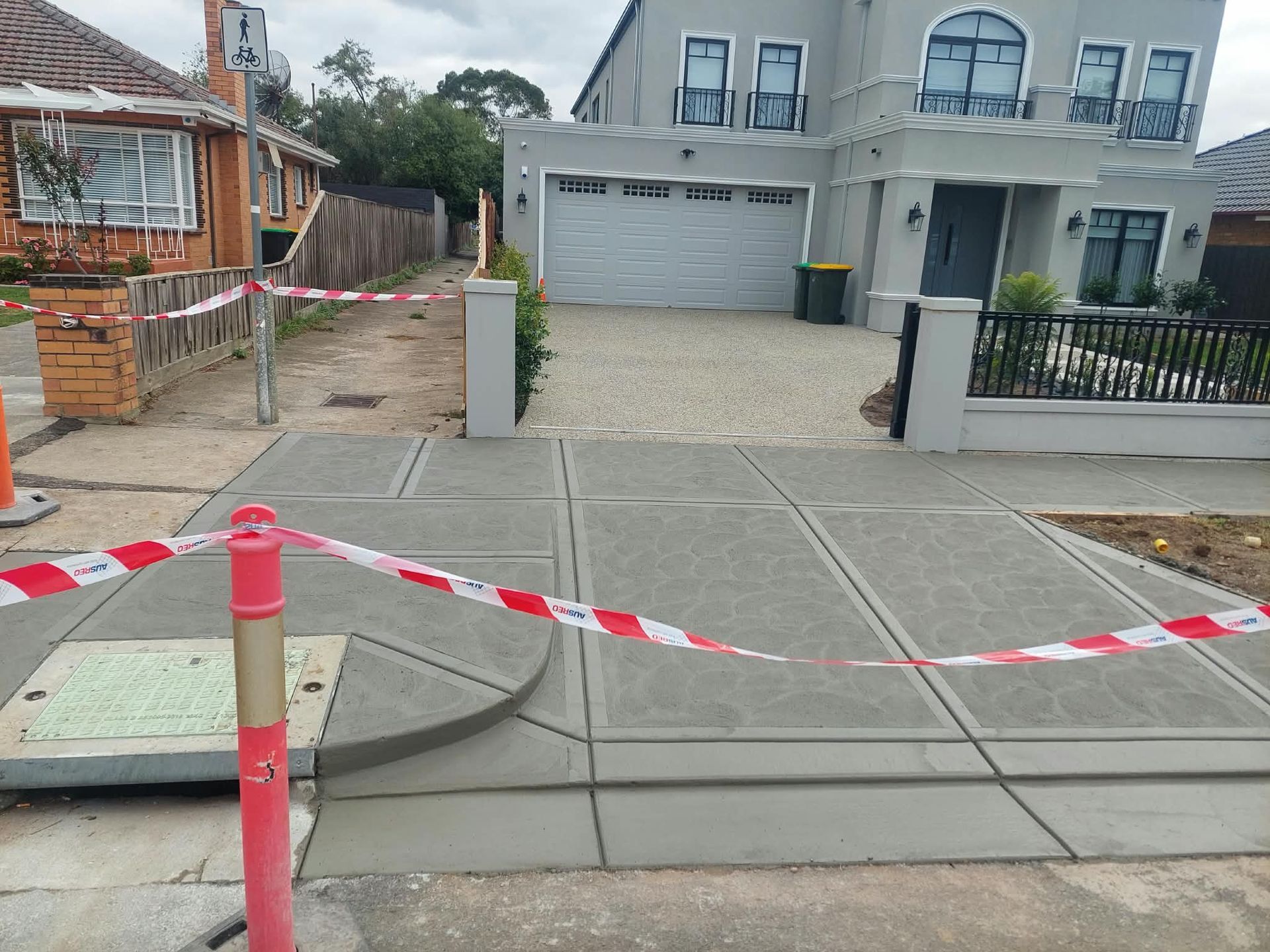 Cordoned-off new driveway and front yard with red-and-white tape in a residential neighborhood