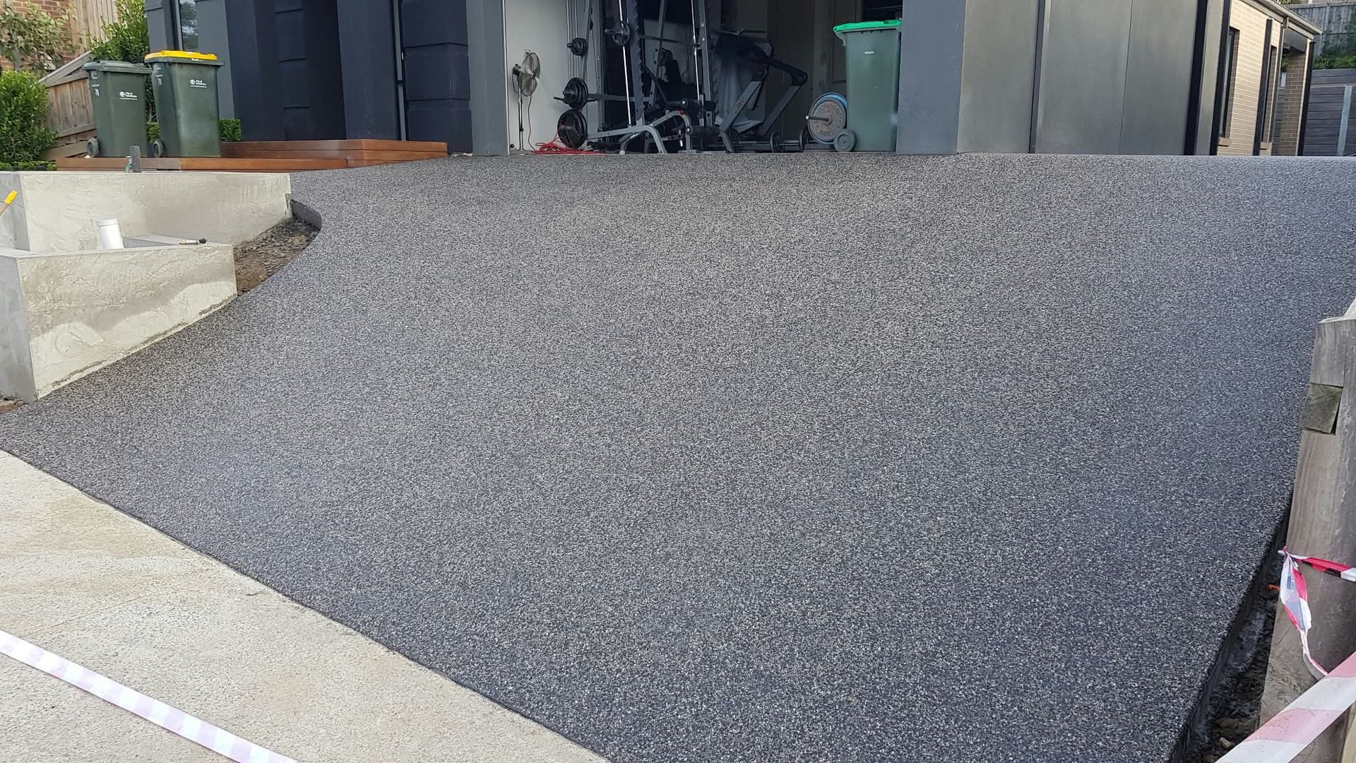 Freshly paved gray asphalt driveway leading to a garage entrance