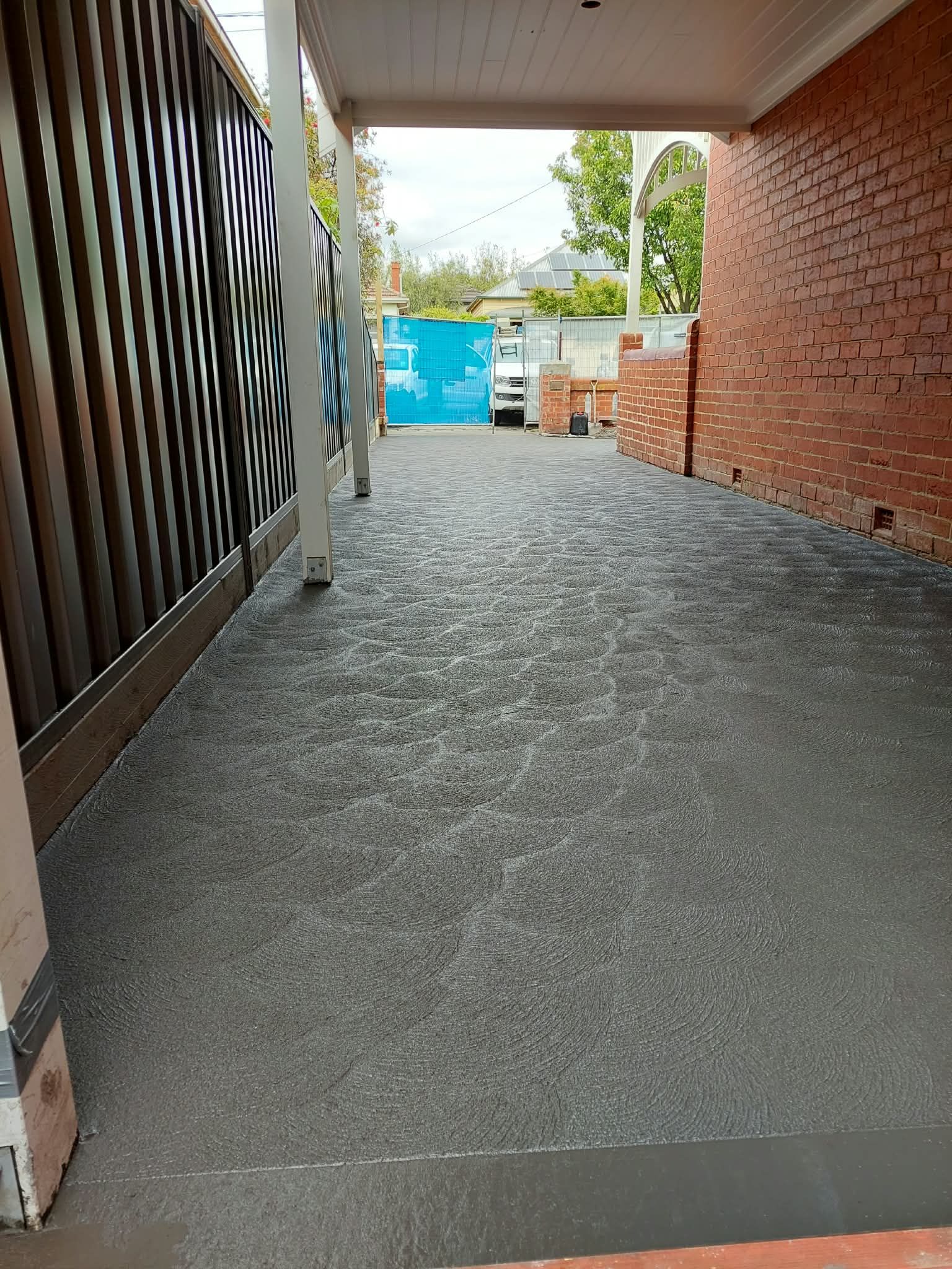 Covered walkway with gravel floor, brick wall, and a blue gate at the end