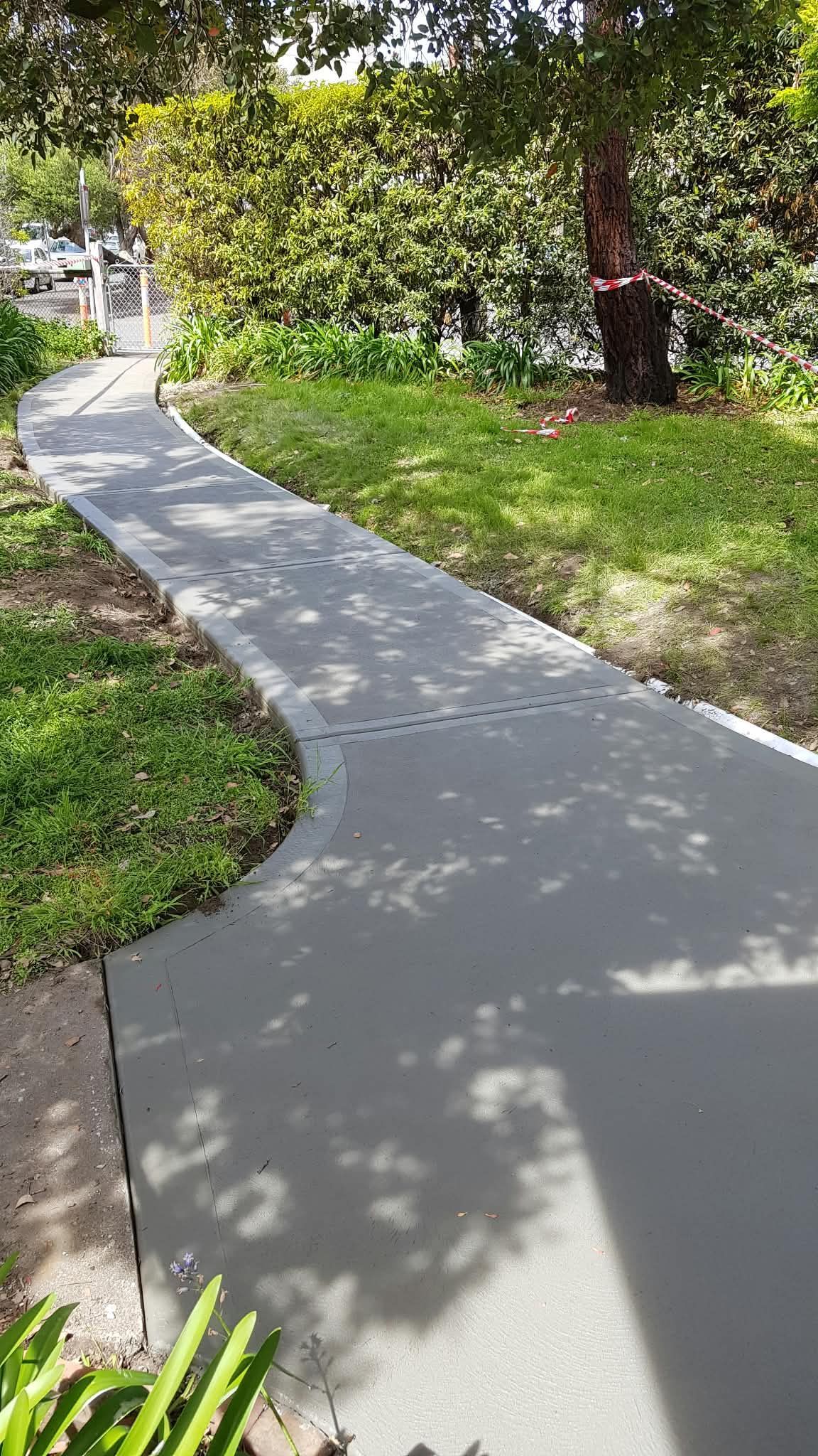 Curved concrete path winding through a green, tree-lined park