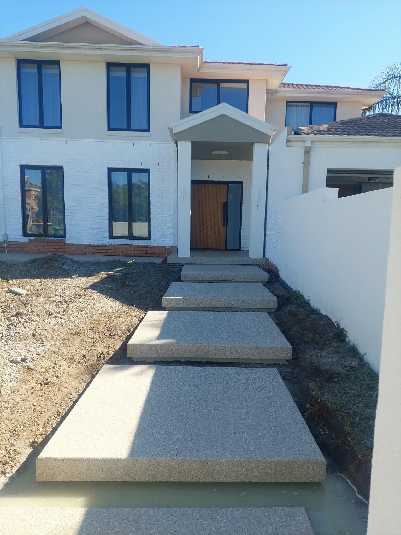 Modern white two-story house with a front path of stepping stones and a covered entryway
