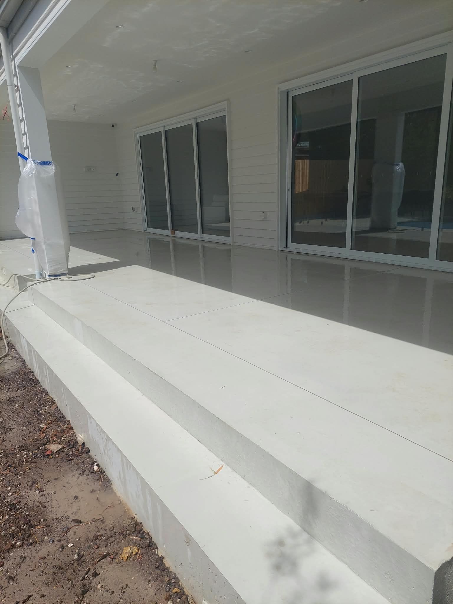 White concrete patio steps beside sliding glass doors on a covered porch
