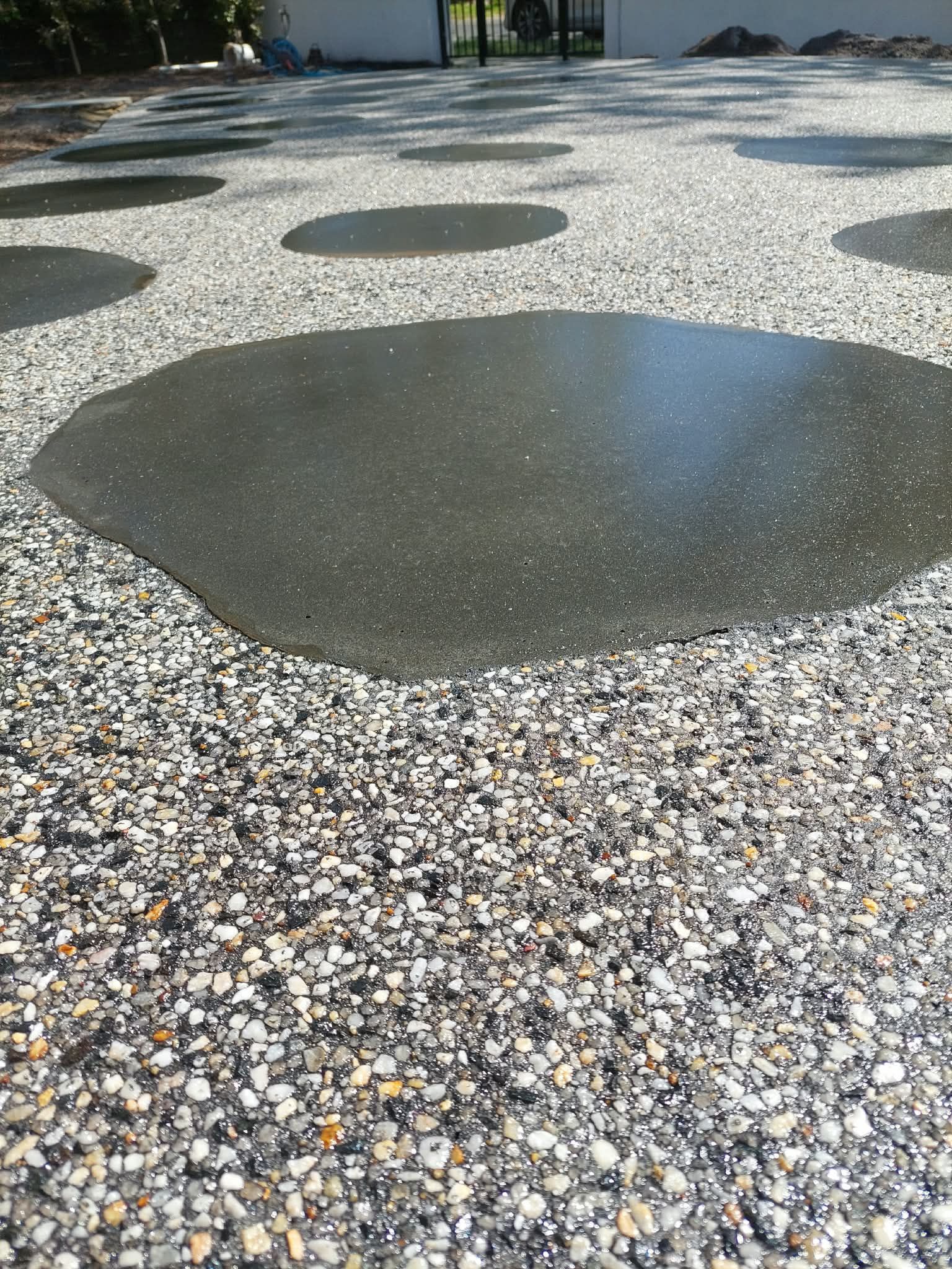 Gravel courtyard with several dark circular wet spots on the ground