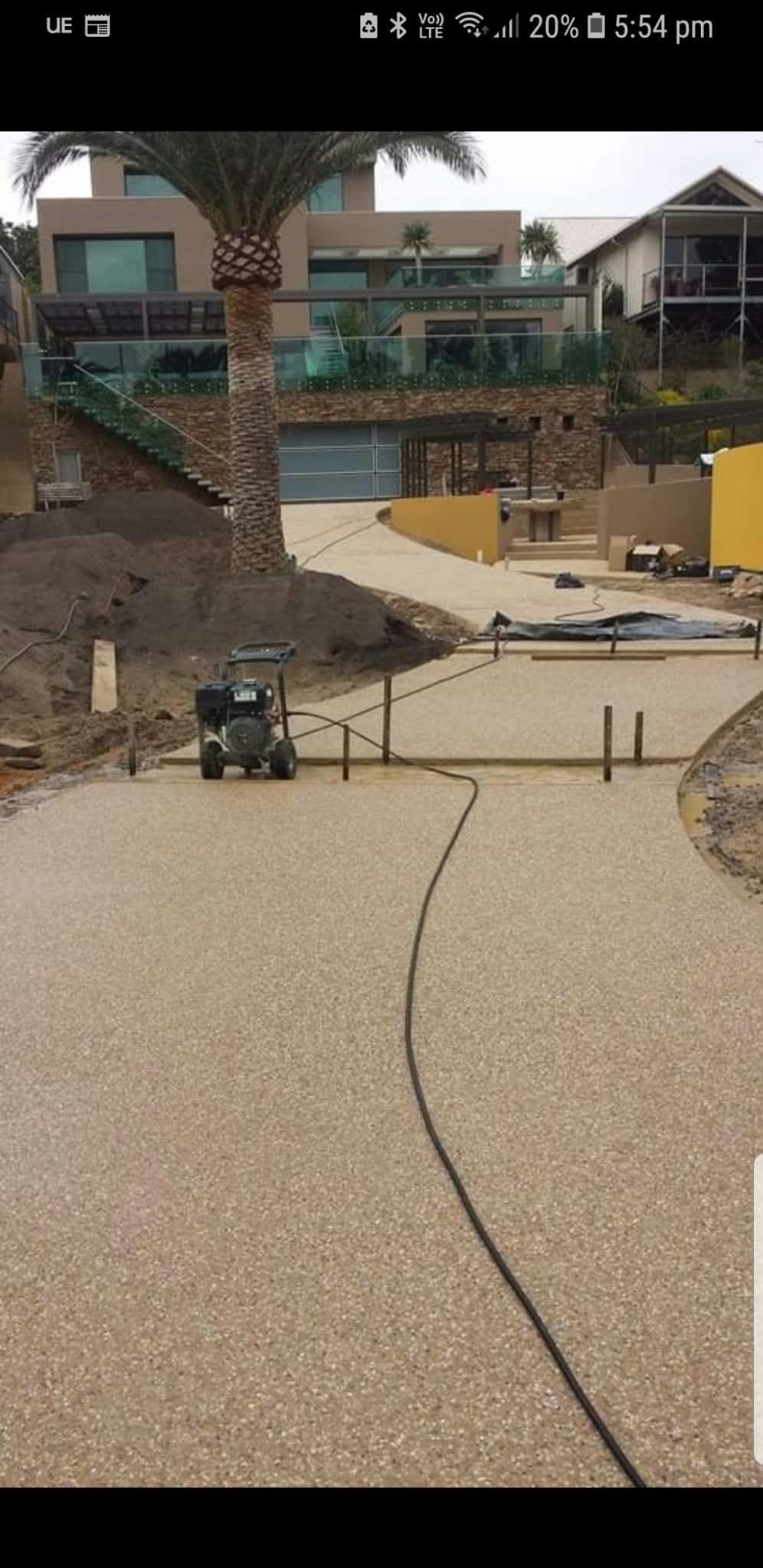 Backyard patio with a curved stone walkway, stairs, and a pool under construction in the background