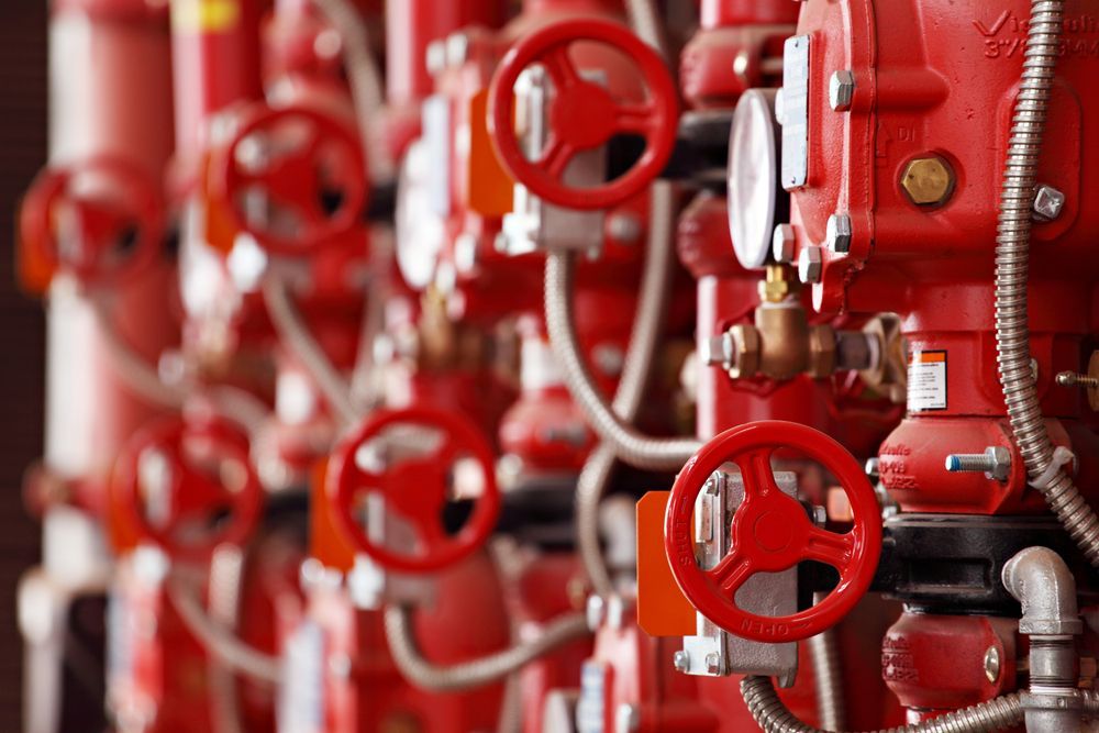 A Row of Red Valves and Pipes in a Factory — J & N Plumbing Pty Ltd In Kootingal, NSW
