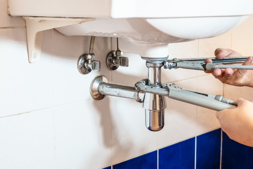 A Person is Fixing a Sink With a Wrench — J & N Plumbing Pty Ltd In Gunnedah, NSW