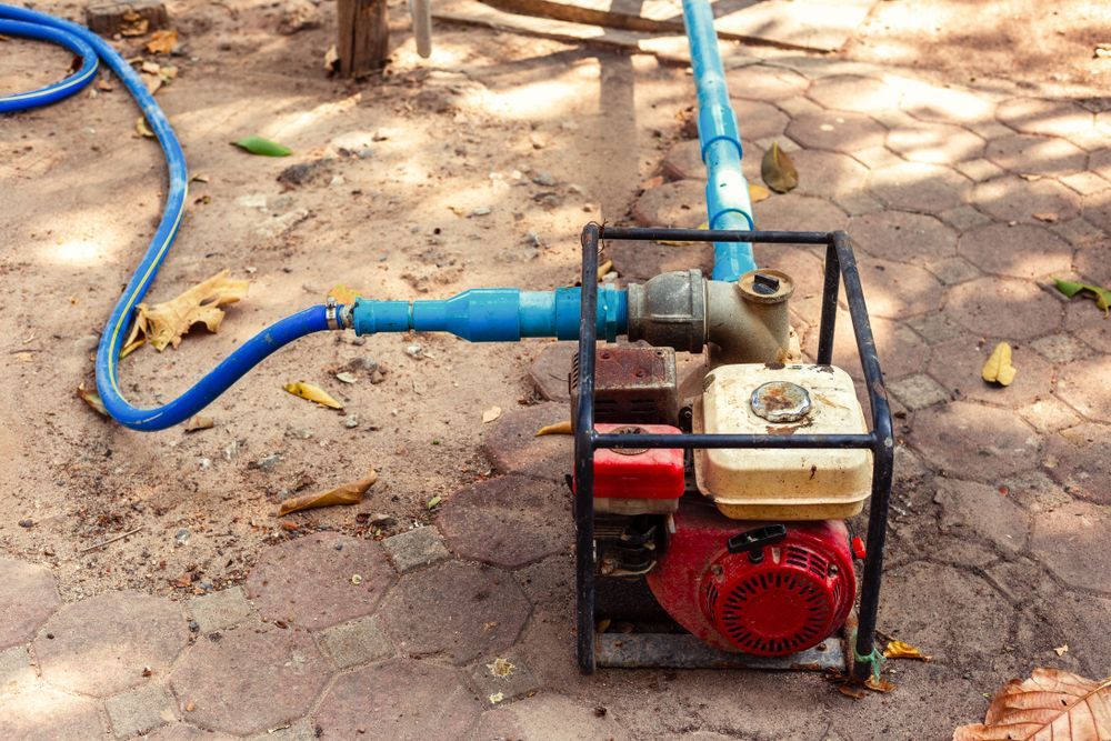 A Water Pump With a Hose Attached to It is Sitting on the Ground — J & N Plumbing Pty Ltd In Gunnedah, NSW