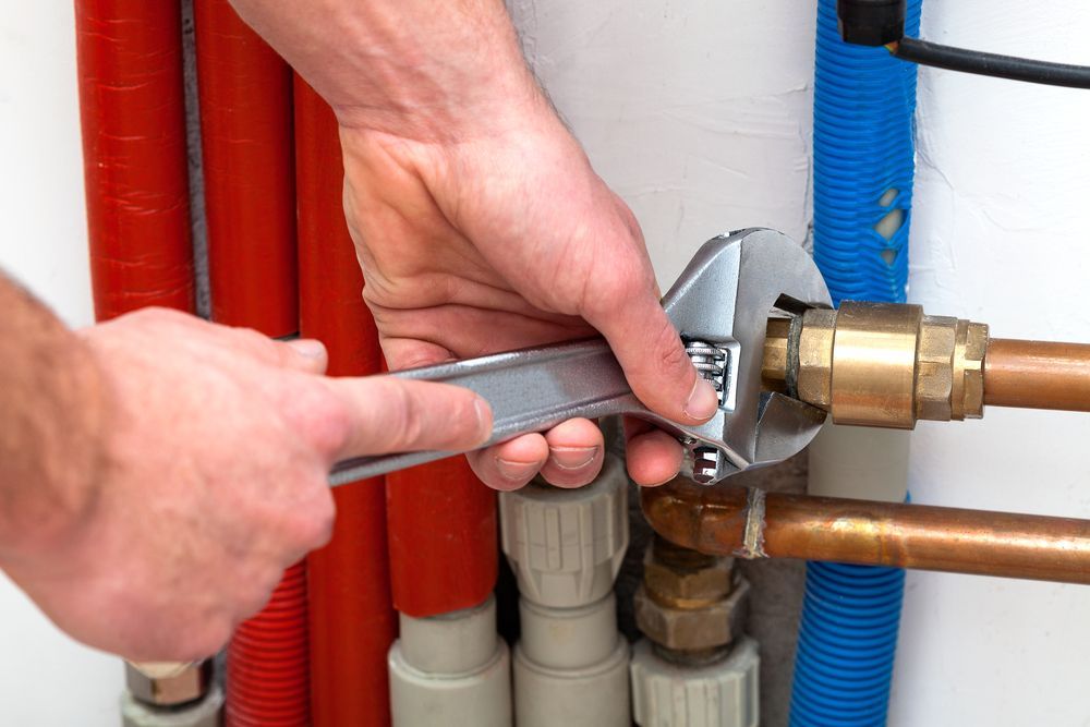 A Plumber is Fixing a Pipe With a Wrench — J & N Plumbing Pty Ltd In Manilla, NSW