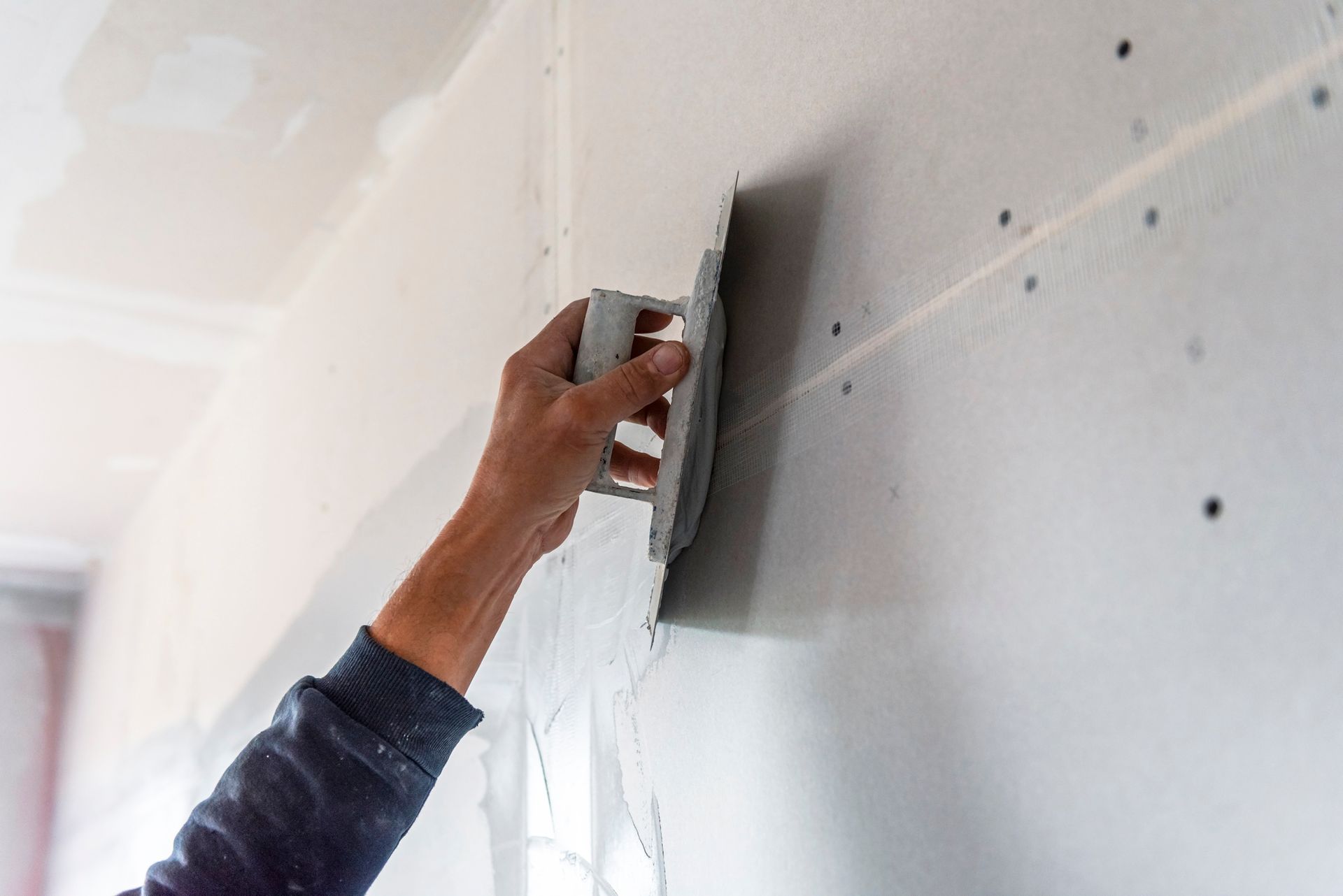 Close-up of a worker's hand from a plastering company, using a plaster tool for indoor walls.