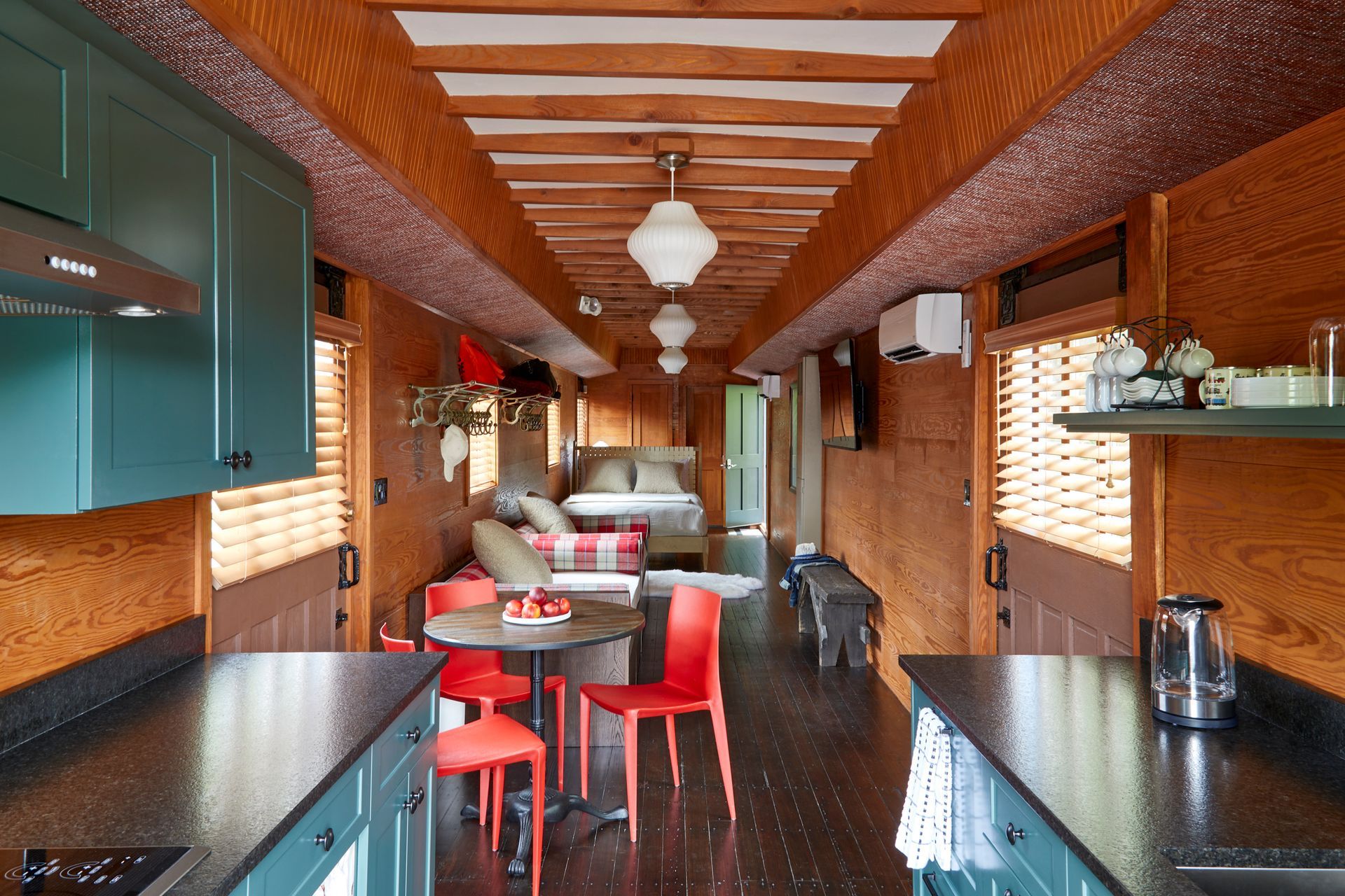 Empty retro diner interior with red stools, wooden ceiling, and long counter tables