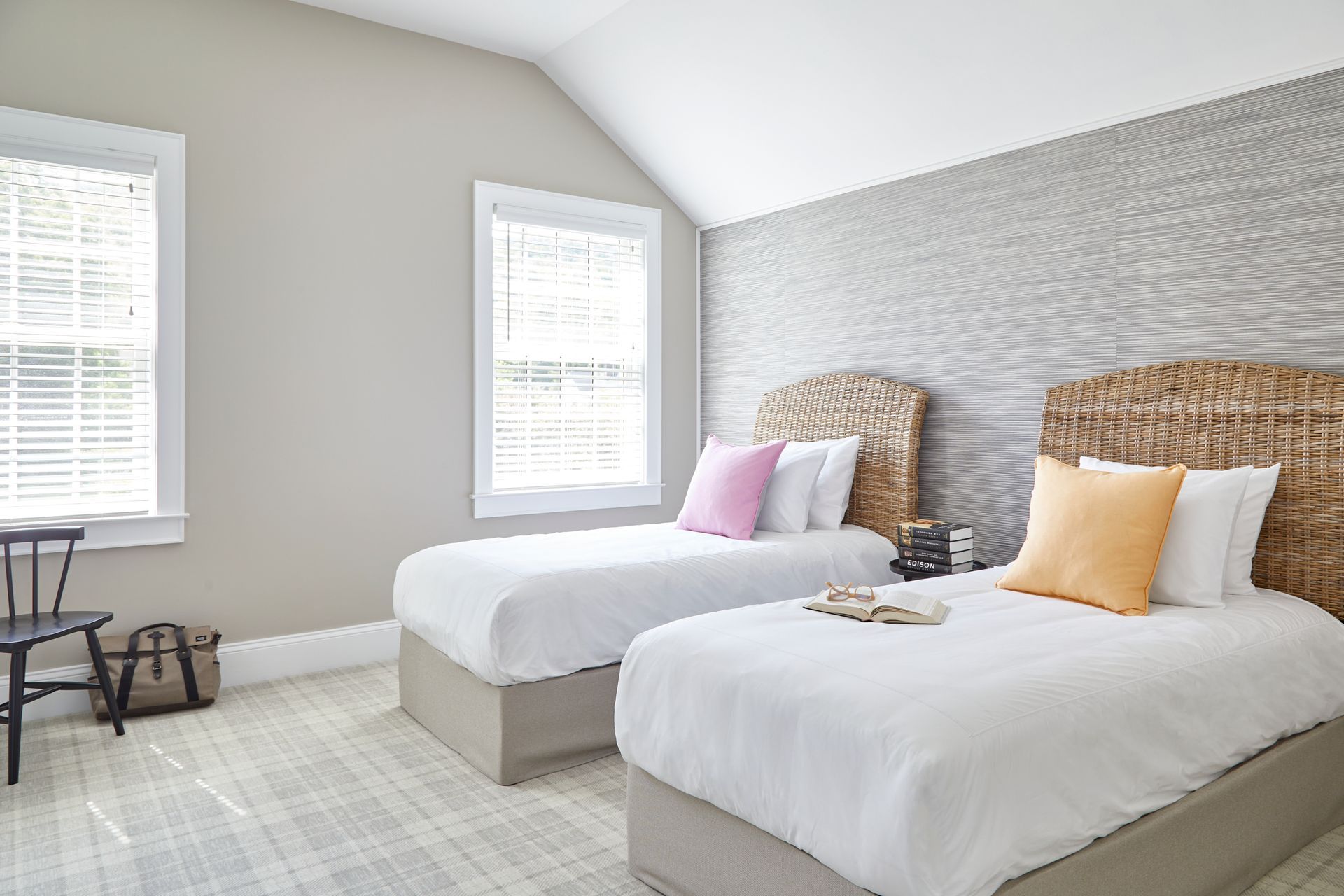Bright twin bedroom with two wicker beds, white bedding, gray patterned wall, and windows with blinds.