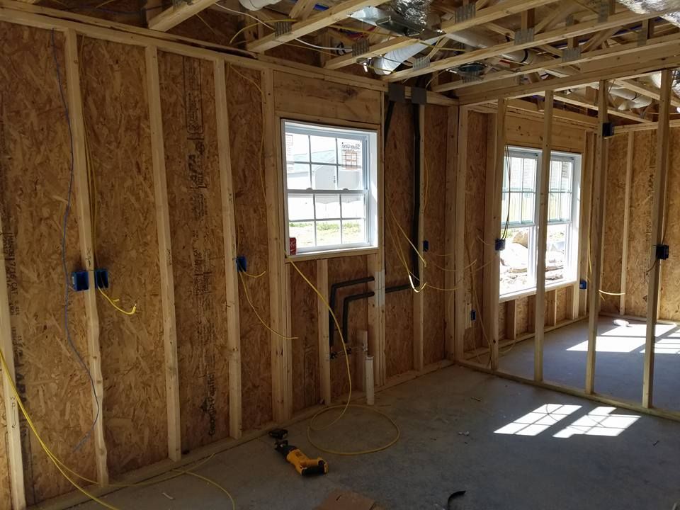Interior of a building under construction, showing wooden framing, windows, and electrical wiring.
